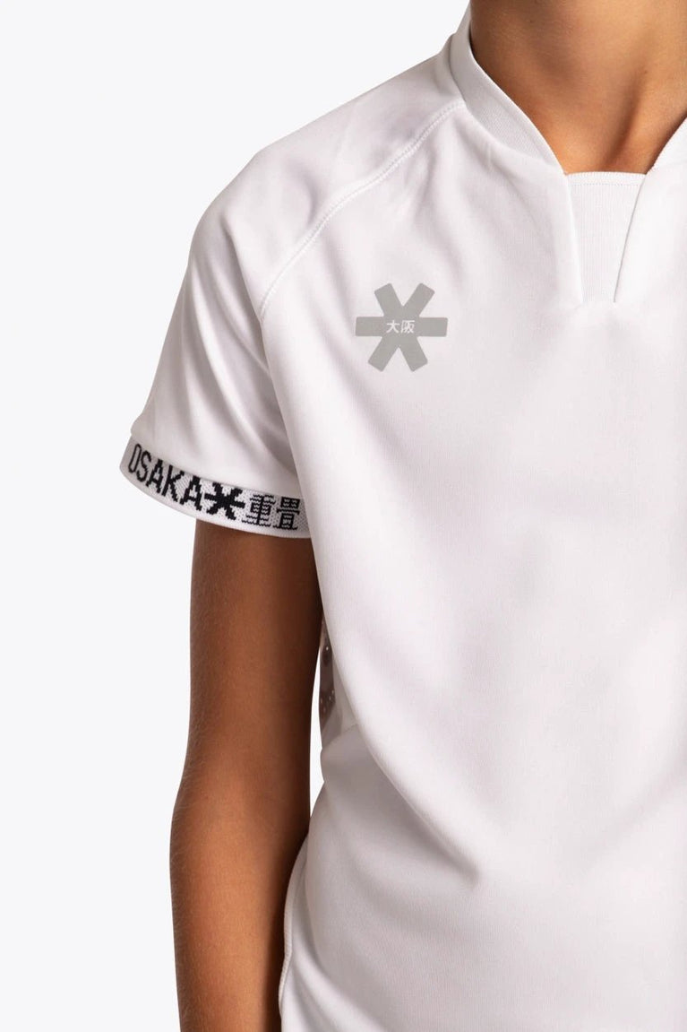 Boy wearing the Osaka Kids Jersey in white. Front detail logo view