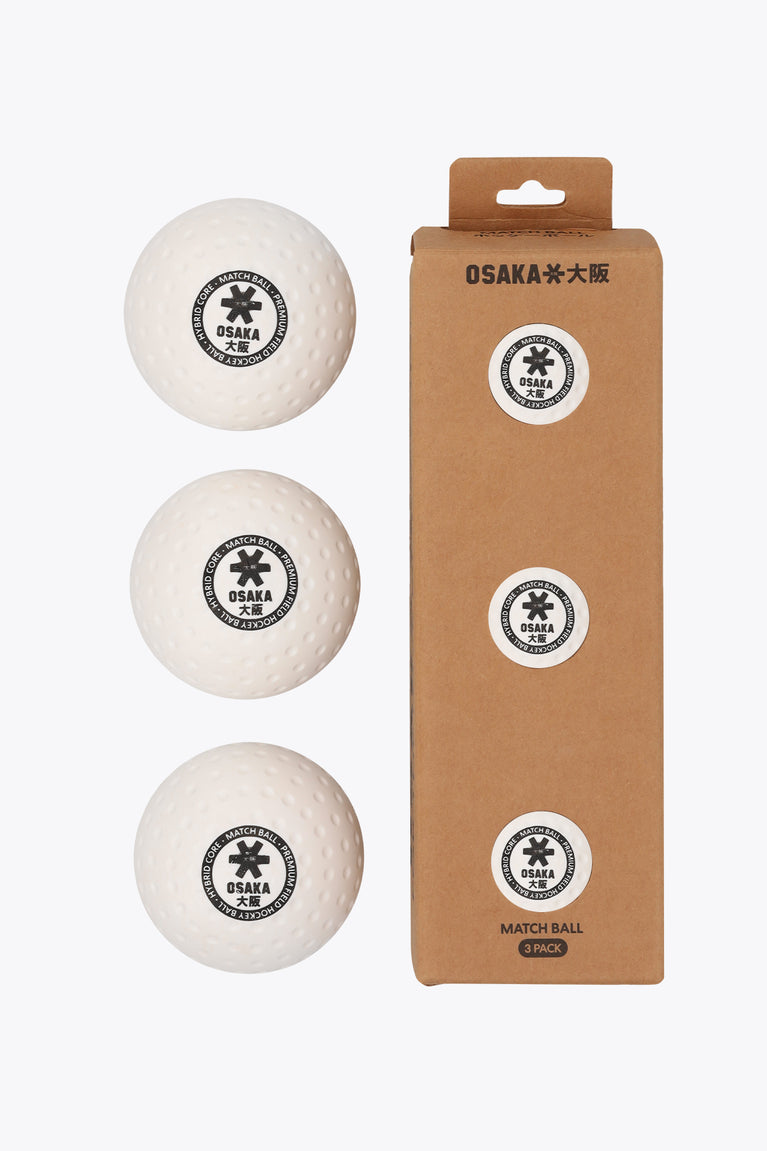 Three white Osaka field hockey match balls next to their kraft cardboard 3-pack box