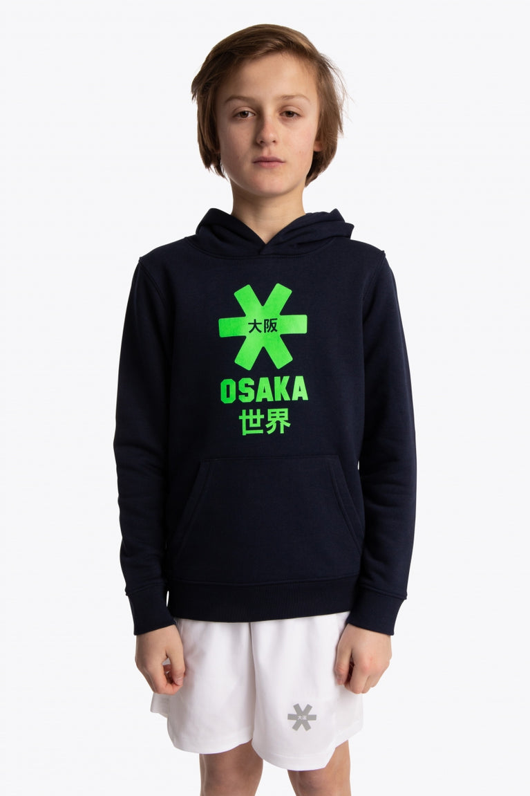Boy wearing the Osaka kids hoodie in navy with green star logo. Front view