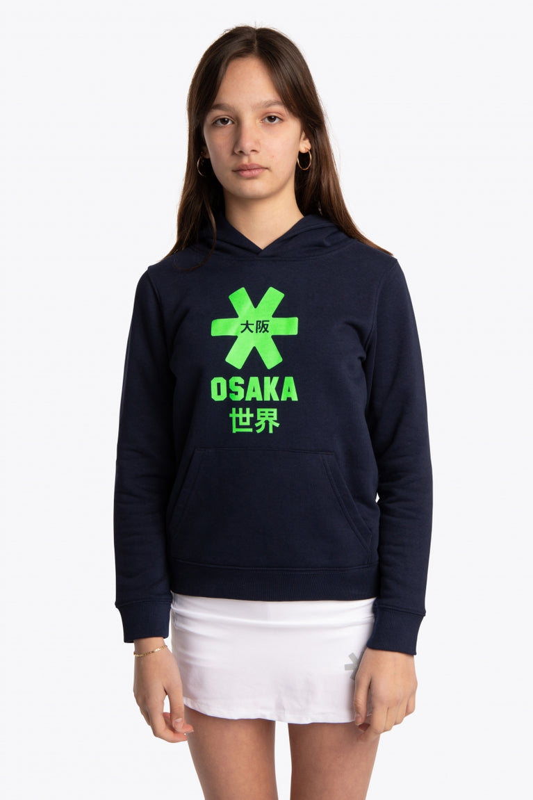 Girl wearing the Osaka kids hoodie in navy with green star logo. Front view