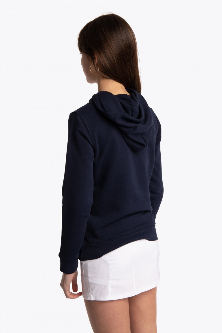 Girl wearing the Osaka kids hoodie in navy with green star logo. Side/back view