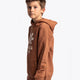 Boy wearing the Osaka kids vintage hoodie in caramel with logo in white. Side/front view
