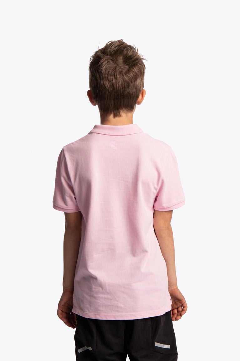 Boy wearing the Osaka kids polo in cotton pink with logo in white. Back view