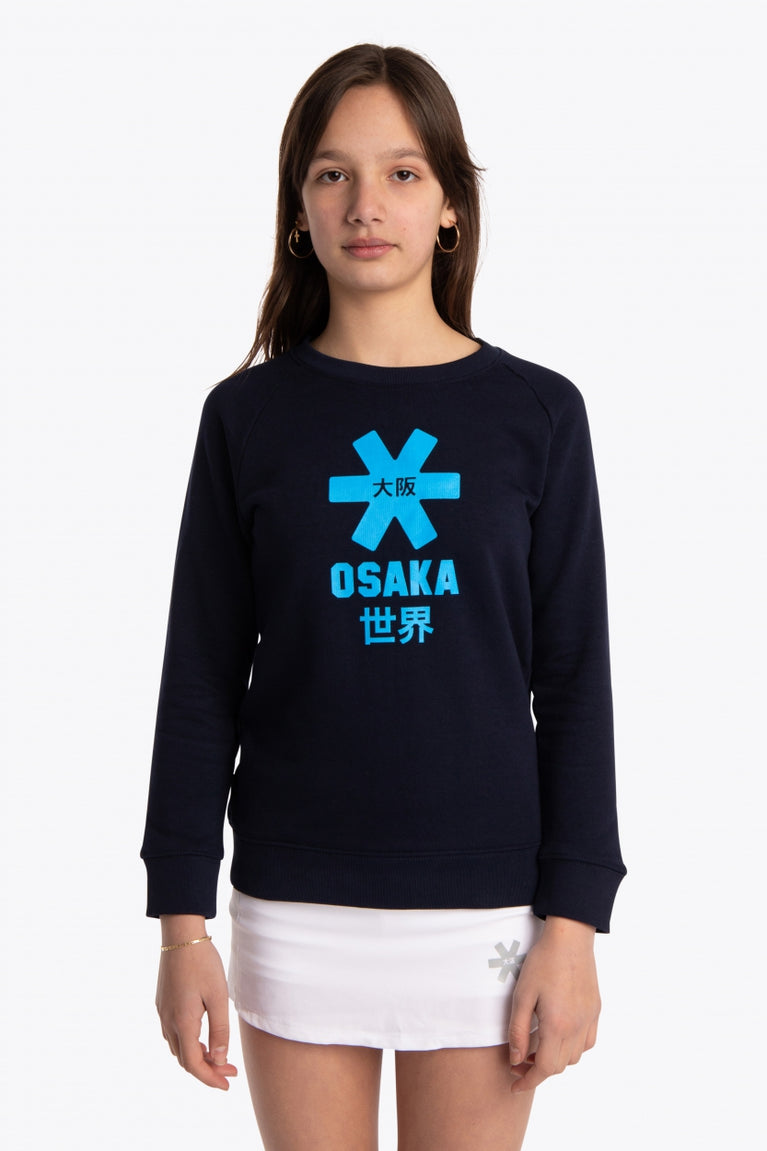 Girl wearing the Osaka kids sweater in navy with logo in blue. Front view