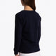 Girl wearing the Osaka kids sweater in navy with logo in blue. Side/back view