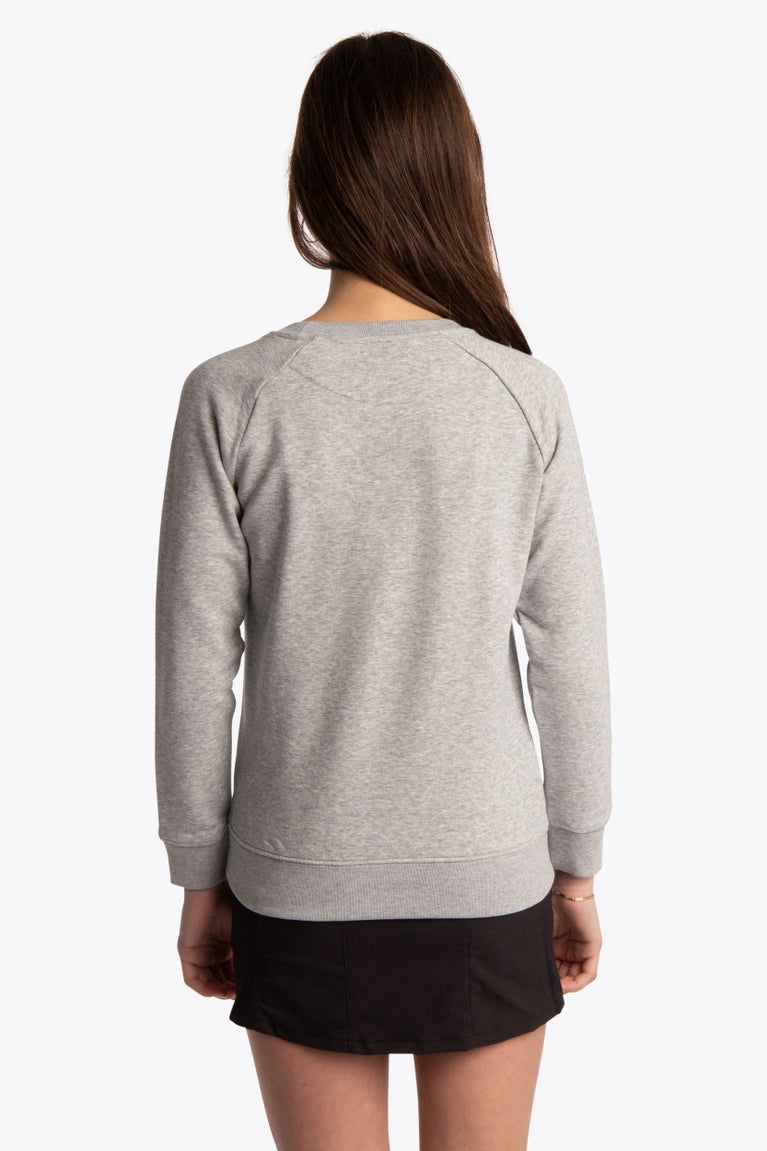 Girl wearing the Osaka kids sweater in grey with logo in blue. Back view