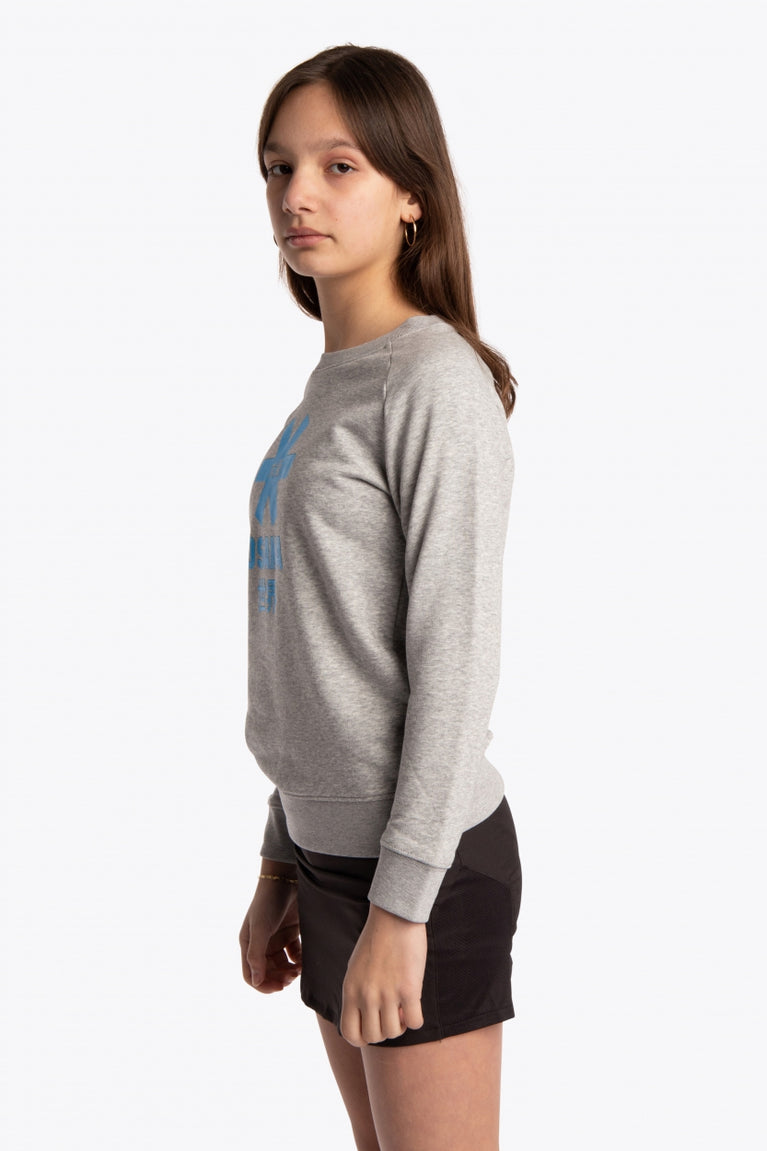 Girl wearing the Osaka kids sweater in grey with logo in blue. Side view