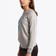 Girl wearing the Osaka kids sweater in grey with logo in blue. Side view