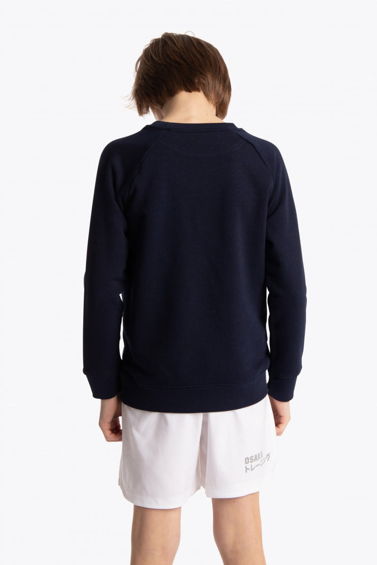 Boy wearing the Osaka kids sweater in navy with logo in green. Back view