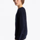 Boy wearing the Osaka kids sweater in navy with logo in green. Side view