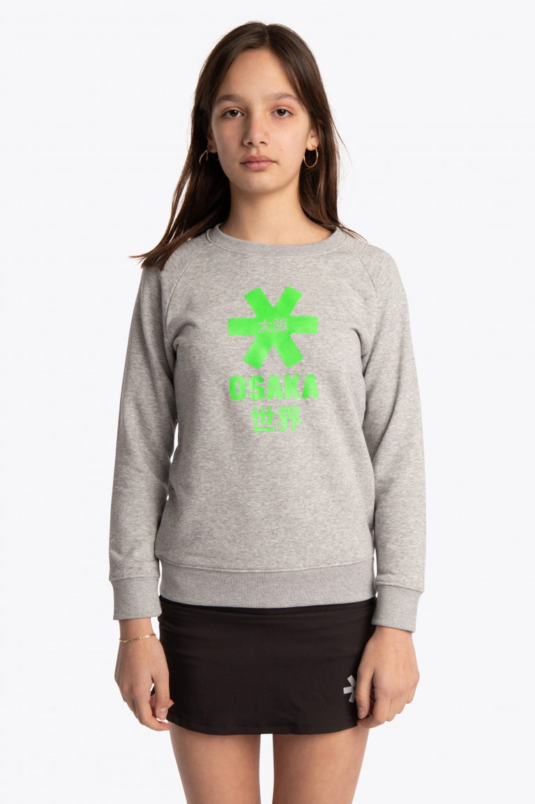 Girl wearing the Osaka kids sweater in grey with logo in green. Front view