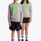 Boy and girl wearing the Osaka kids sweater in grey with logo in green. Front full view
