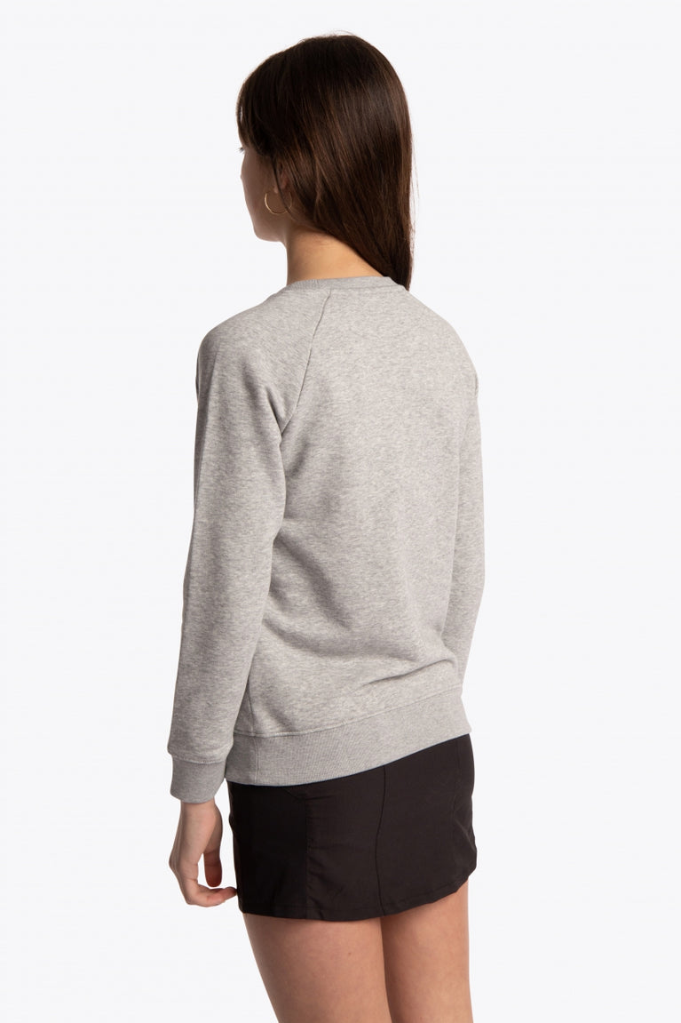 Girl wearing the Osaka kids sweater in grey with logo in green. Back/side view