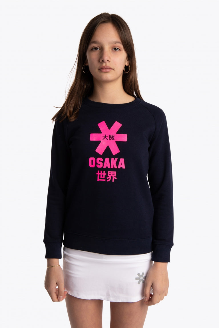 Girl wearing the Osaka kids sweater in navy with pink logo. Front view