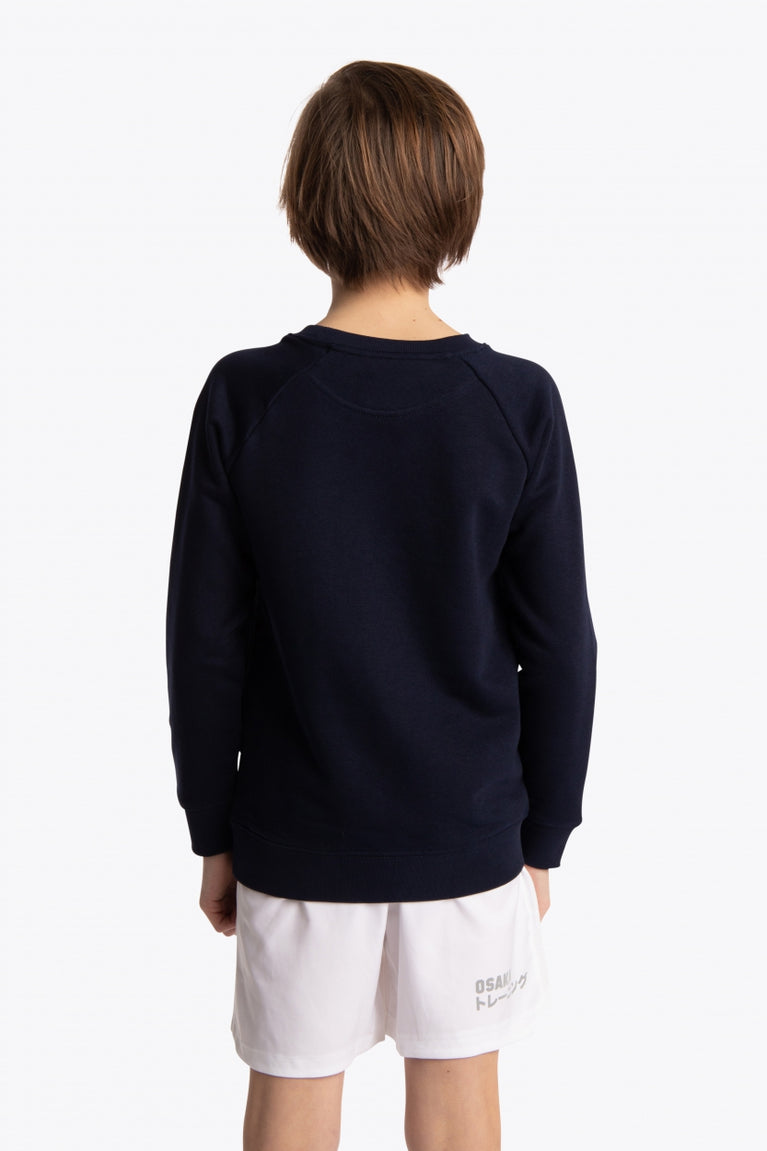Boy wearing the Osaka kids sweater in navy with pink logo. Back view