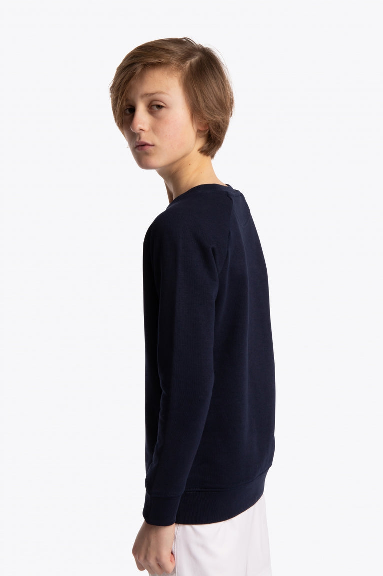 Boy wearing the Osaka kids sweater in navy with pink logo. Side/back view