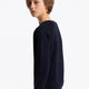 Boy wearing the Osaka kids sweater in navy with pink logo. Side/back view