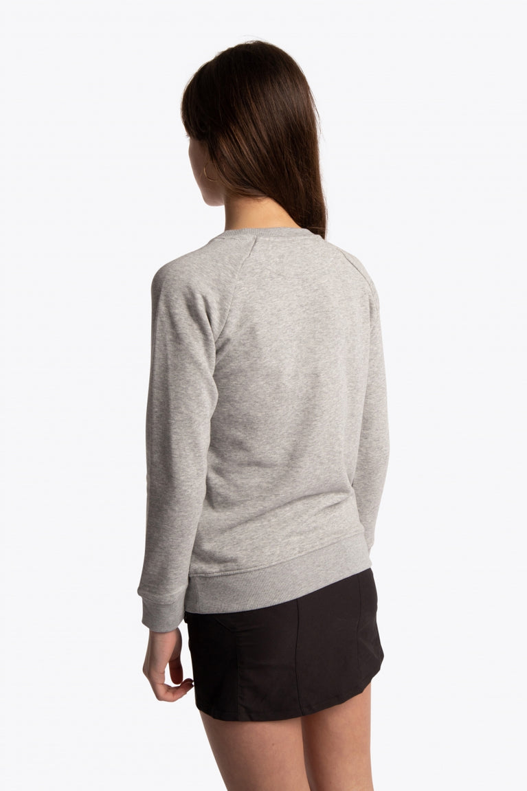 Girl wearing the Osaka kids sweater in grey with pink logo. Side/back view