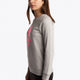 Girl wearing the Osaka kids sweater in grey with pink logo. Side view
