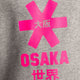 Osaka kids sweater in grey with pink logo. Detail view logo