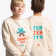 Boy and girl wearing the Osaka kids pixo sweater in natural raw with orange and blue logo. Front and back view