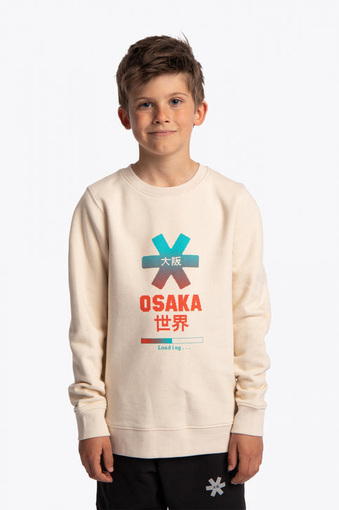 Boy and girl wearing the Osaka kids pixo sweater in natural raw with orange and blue logo. Front and back view