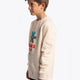 Boy wearing the Osaka kids pixo sweater in natural raw with orange and blue logo. Side view