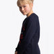 Girl wearing the Osaka kids worldcup sweater in navy with orange logo. Side view