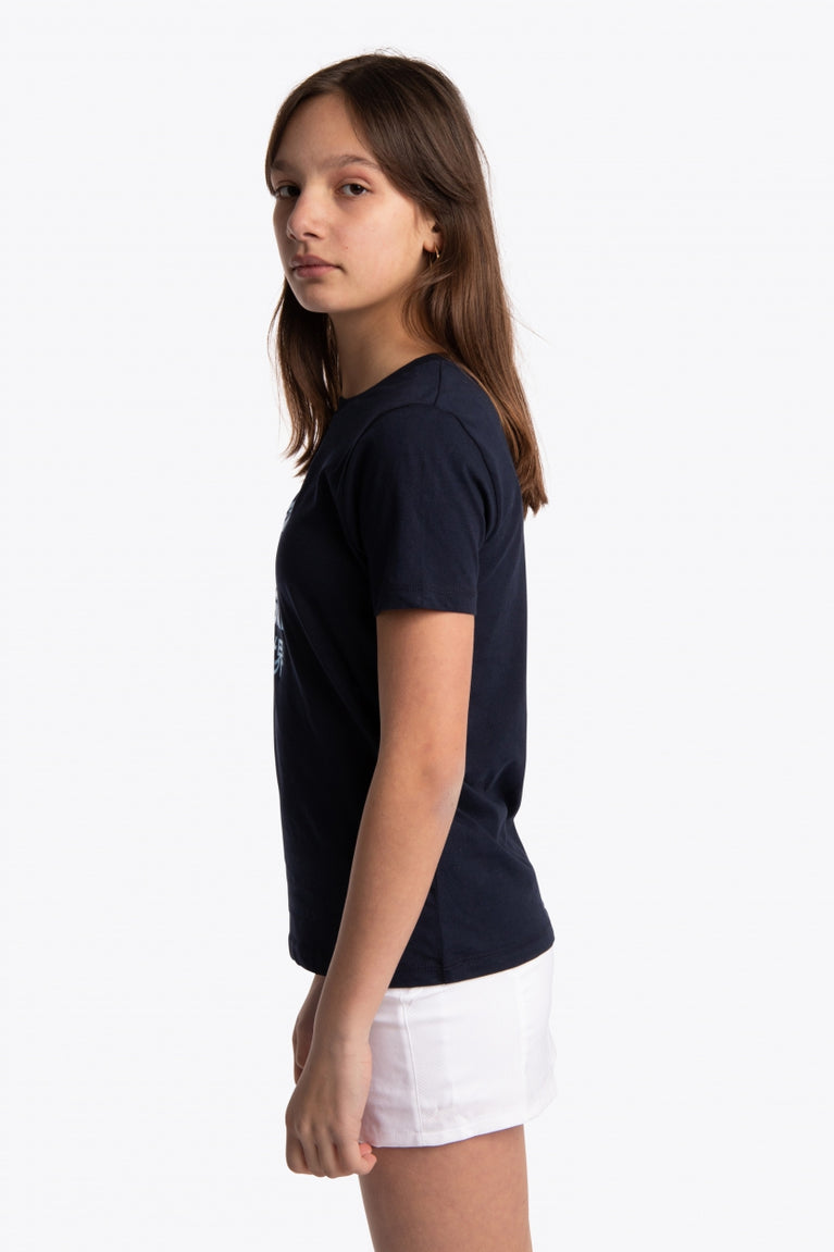 Girl wearing the Osaka kids tee short sleeve navy with logo in blue. Side view
