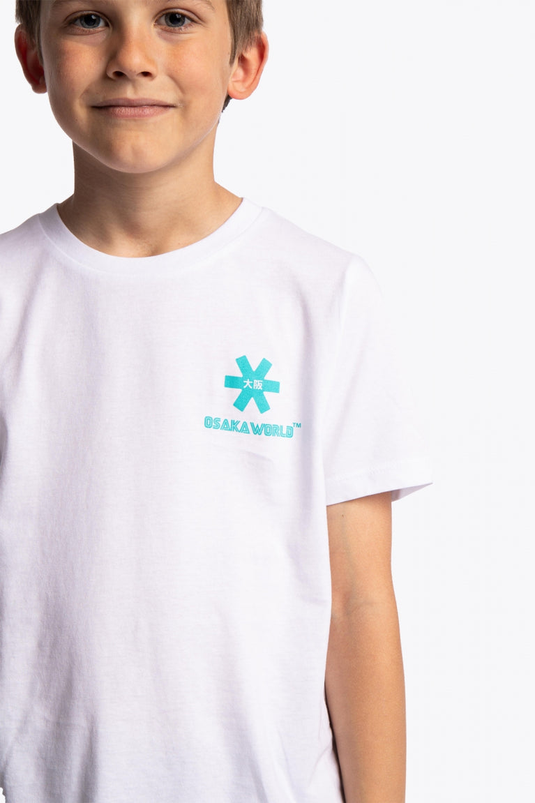 Boy wearing the Osaka kids service games tee short sleeve white with logo in blue. Detail view logo front