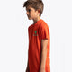 Boy wearing the Osaka kids service games tee short sleeve orange with logo in green. Side view
