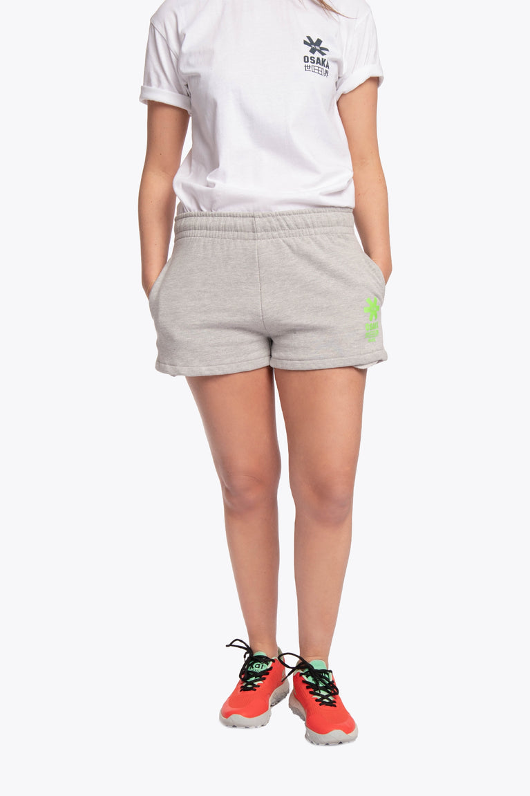 Woman wearing the Osaka women shorts in grey with neon green logo. Front view