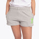 Woman wearing the Osaka women shorts in grey with neon green logo. Front view