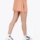 Woman wearing the Osaka women ball skort in peach with logo in grey. Back view