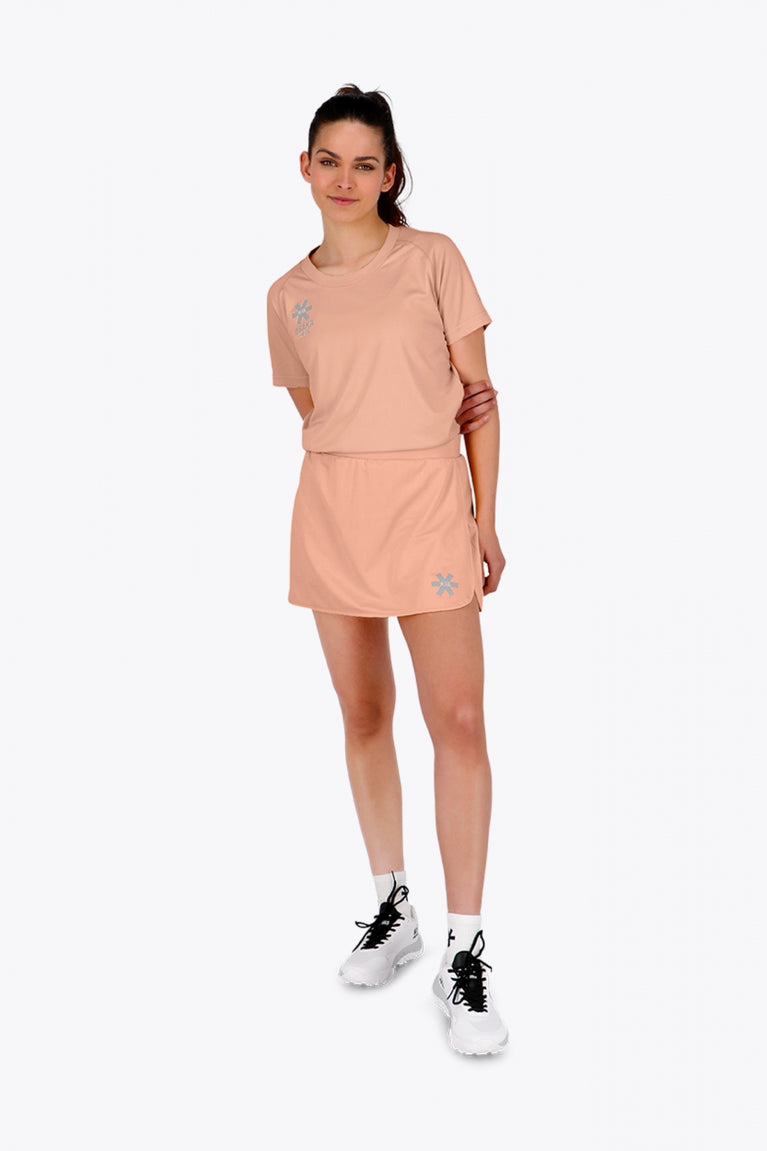 Woman wearing the Osaka women ball skort in peach with logo in grey. Front view
