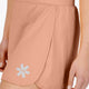Woman wearing the Osaka women ball skort in peach with logo in grey. Detail side view