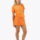 Woman wearing the Osaka women ball skort in orange with logo in white. Front view