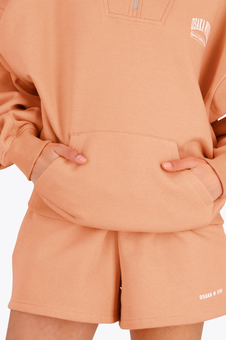 Osaka women half zip sweater in peach with white logo. Front view