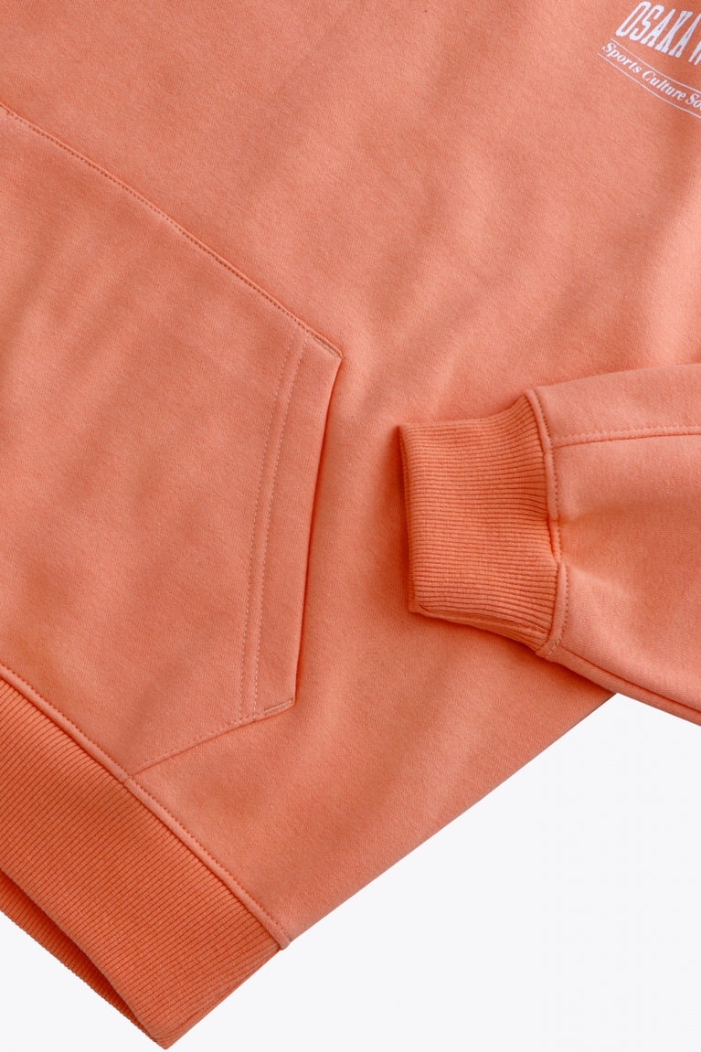 Osaka women half zip sweater in peach with white logo. Front flatlay detail sleeve view