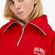 Woman wearing the Osaka women half zip sweater in red with white logo. Front detail neck view