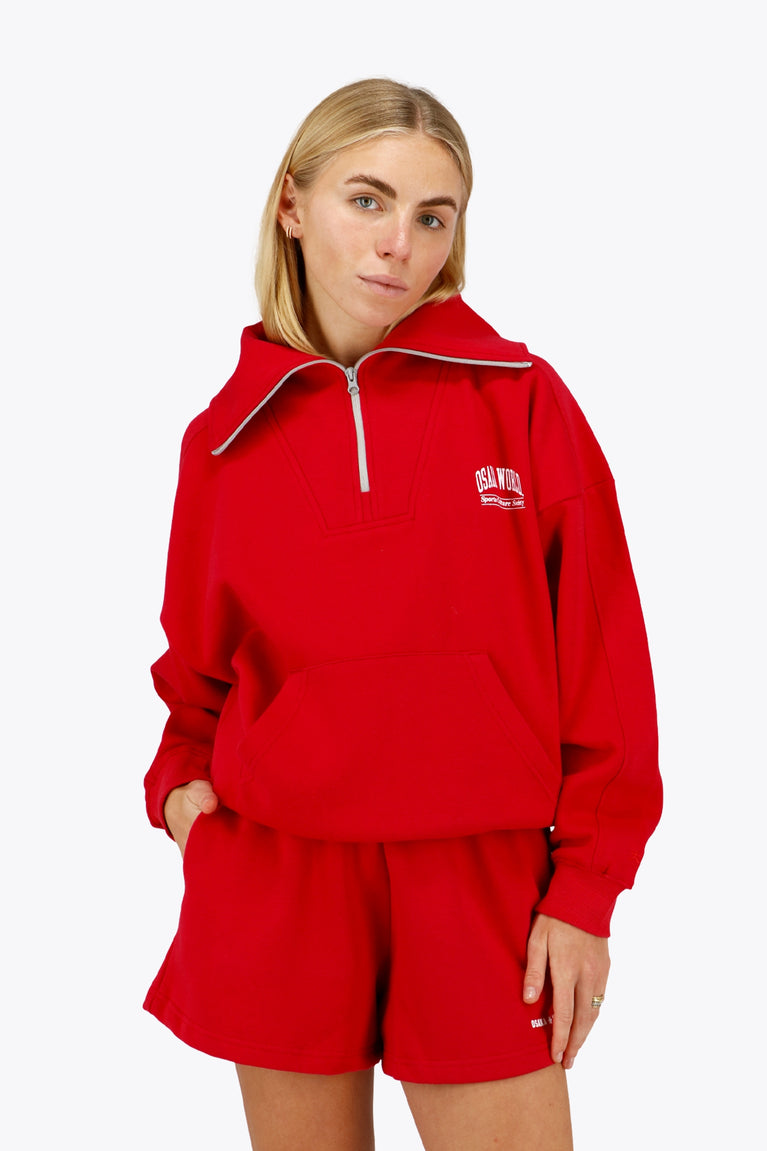 Woman wearing the Osaka women half zip sweater in red with white logo. Front view