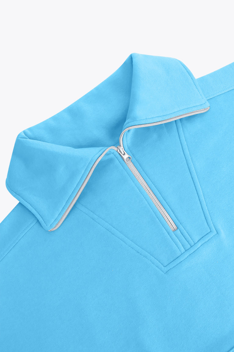 Osaka women half zip sweater in light blue with white logo. Front detail neck flatlay view