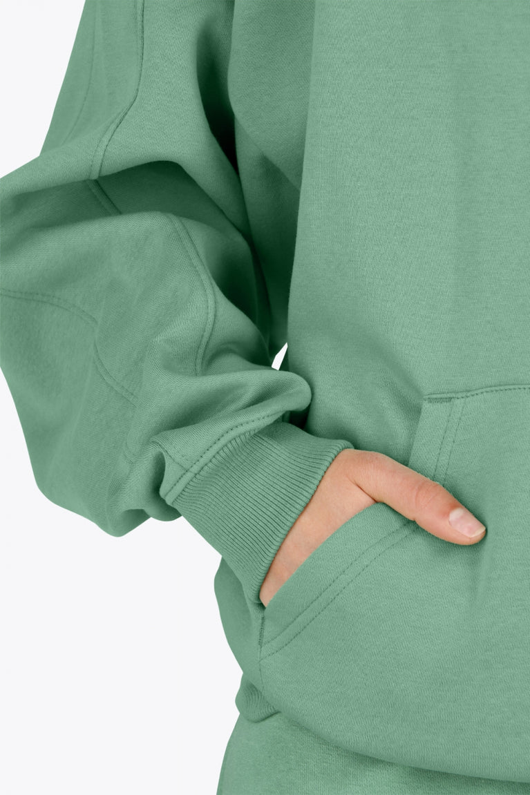 Woman wearing theOsaka women half zip sweater green. Front detail sleeve view