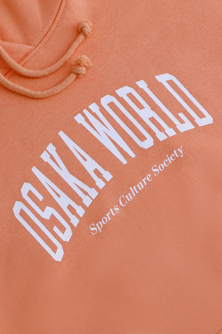 Osaka women hoodie in peach with white logo. Front detail logo view