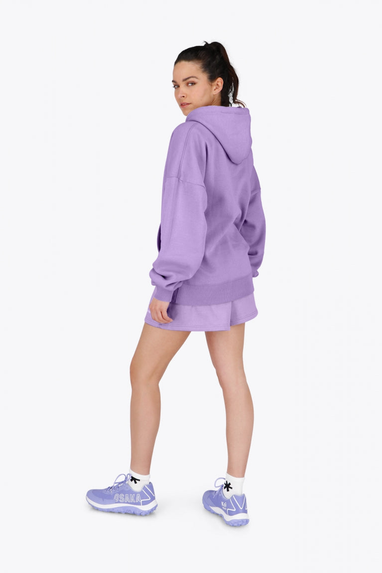 Woman wearing the Osaka women hoodie in light purple with white logo. Back / side view