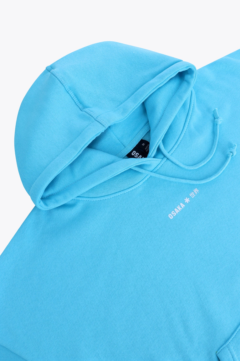 Osaka women hoodie in light blue with white logo. Front detail neck flatlay view