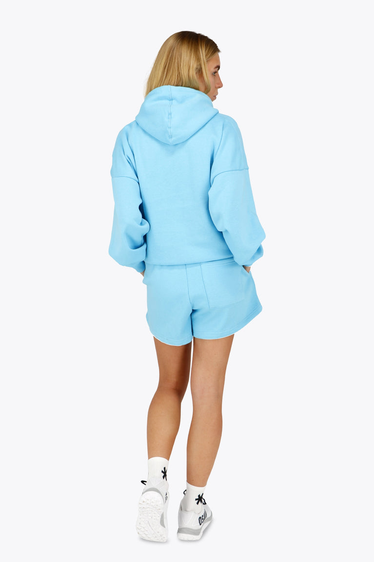 Woman wearing the Osaka women hoodie in light blue with white logo. Back view