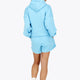 Woman wearing the Osaka women hoodie in light blue with white logo. Back view