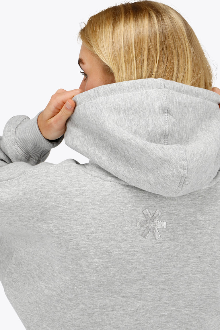 Woman wearing the Osaka women hoodie in heather grey with white logo. Back detail cap and logo view