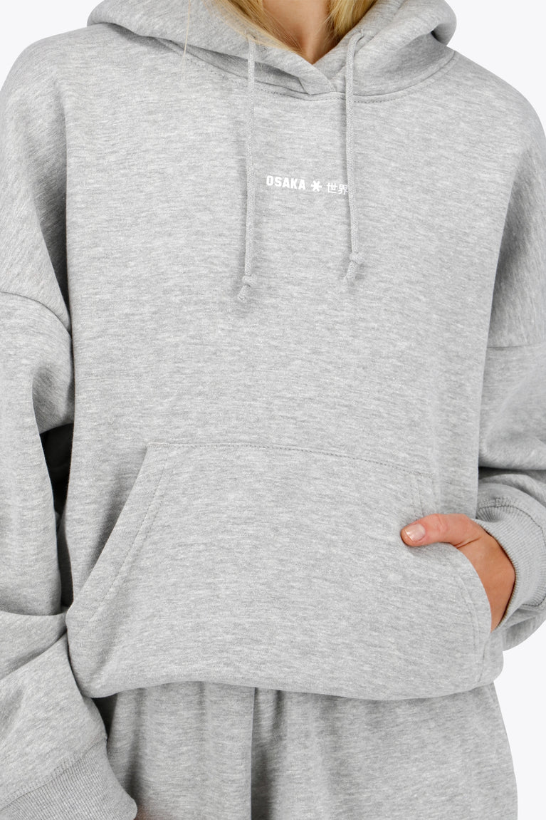 Woman wearing the Osaka women hoodie in heather grey with white logo. Front view